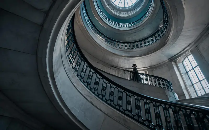 A civic staircase seen from below, spiralling up through the void
